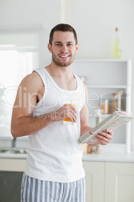 Portrait of a smiling man drinking orange juice while reading th
