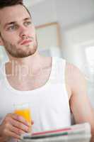 Portrait of a good looking man drinking orange juice while readi