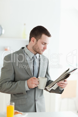 Portrait of a handsome businessman having breakfast while readin