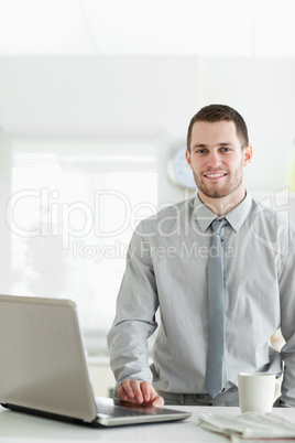 Portrait of a businessman using a laptop while drinking tea