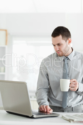 Portrait of a businessman using a notebook while drinking tea