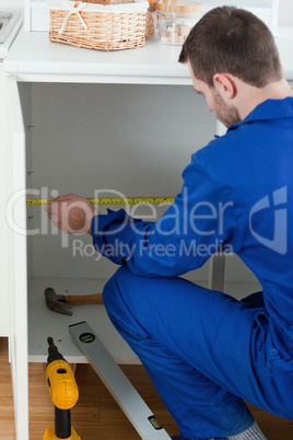 Portrait of a young handyman measuring something