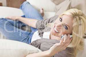 Young Blond Woman Using Cell Phone At Home on Sofa