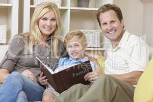 Happy Family Sitting on Sofa Looking at Photo Album