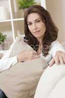 Brunette Woman Sitting Thinking At Home on Sofa