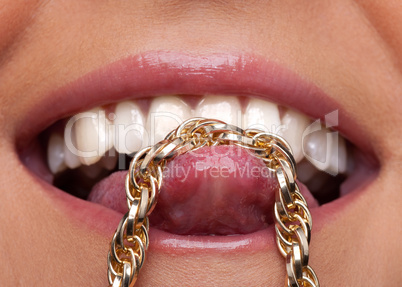 Beauty woman lips and gold chain on tongue