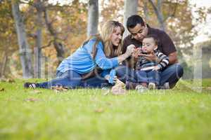 Happy Mixed Race Ethnic Family Playing with Bubbles In The Park