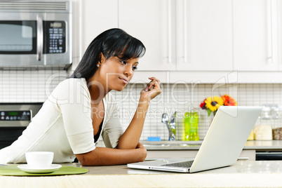 Woman using computer in kitchen