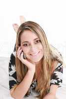 Attractive woman talking on phone lying on the floor at home