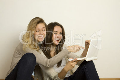 Two attractive friends at home with laptop