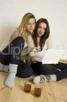 Two attractive friends at home with laptop