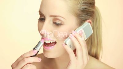 Blonde Lady Using Mobile Phone and applying lipstick