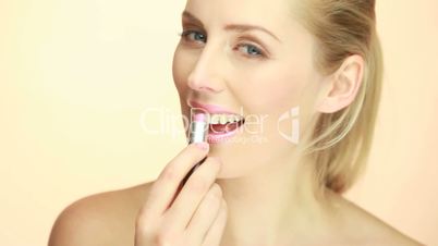 Smiling Glamorous Lady Applying Lipstick in a shade of pink