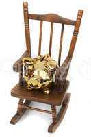 old wooden rocking chair and golden piggy bank on white