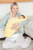 Mother holding her baby that is wrapped into a cover