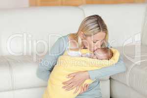 Lovely mother kissing her baby which is wrapped into a cover