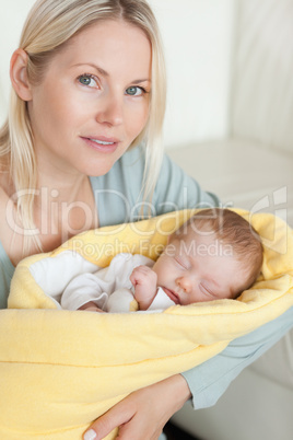 Mom holding her sleeping baby that is wrapped up in a cover