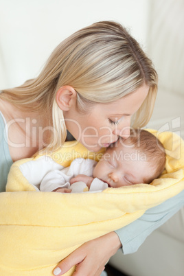 Affectionate mother kissing her baby's forehead