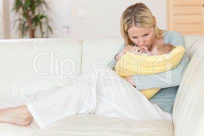 Mother sitting on the couch kissing her baby in her arms