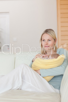 Mother sitting on the couch while holding her baby