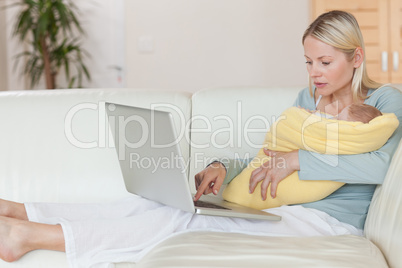 Mother surfing the internet while holding her baby
