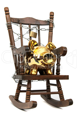 old wooden rocking chair and piggy bank captured with chain and padlock on white