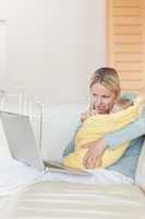 Mother with notebook on the couch holding her baby