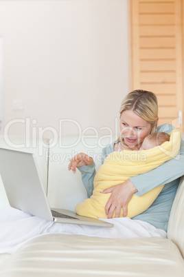 Mother on the couch showing her baby something on the laptop