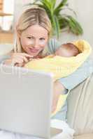Mother in the living room with her baby looking at her laptop