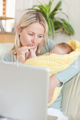 Affectionate mother holding her baby on the sofa