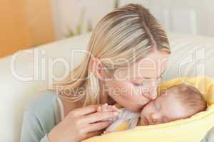 Mother on the sofa kissing her baby