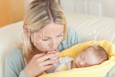 Mother on the sofa kissing her baby's hand
