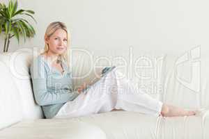 Side view of woman sitting on the sofa with a magazine