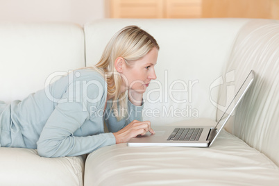 Side view of woman with notebook lying on the sofa