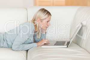 Side view of woman with notebook lying on the sofa