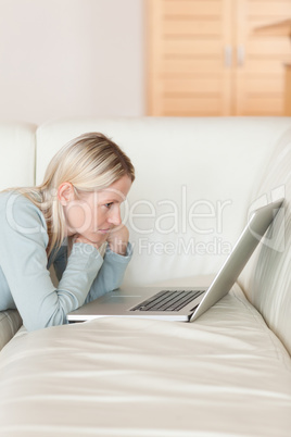 Side view of woman with notebook lying on the couch