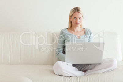 Woman sitting cross legged on the sofa with her notebook
