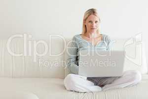 Woman sitting cross legged on the sofa with her notebook