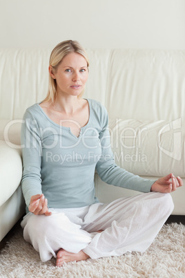 Woman sitting cross legged on the carpet doing yoga