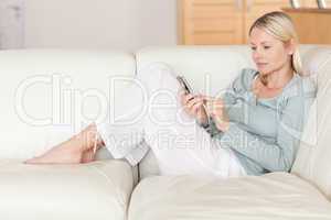 Woman on the sofa typing on her smartphone