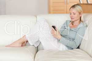Woman on the sofa reading text message on her smartphone