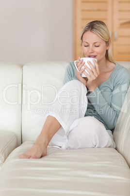 Woman on the sofa taking a sip of coffee