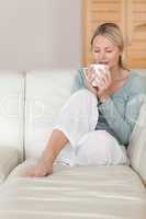 Woman on the sofa taking a sip of coffee
