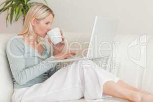 Woman enjoying a sip of coffee while working on her laptop