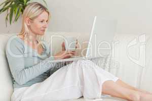 Woman sitting on the couch with a cup of coffee and her laptop