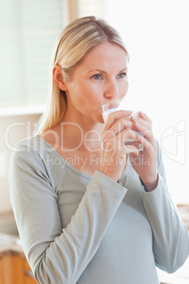 Woman drinking a glass of water in the kitchen