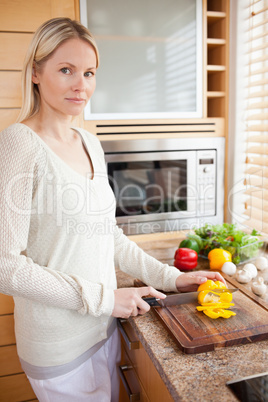 Side view of woman slicing bell pepper in the kitchen