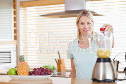 Woman dropping strawberry into the blender