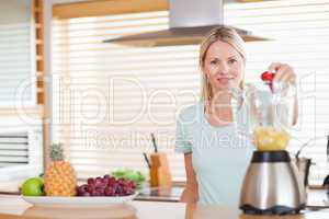 Woman dropping strawberry into the blender