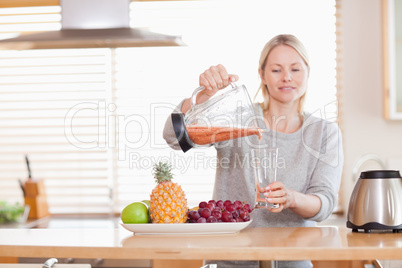 Woman pouring self made juice into a glass